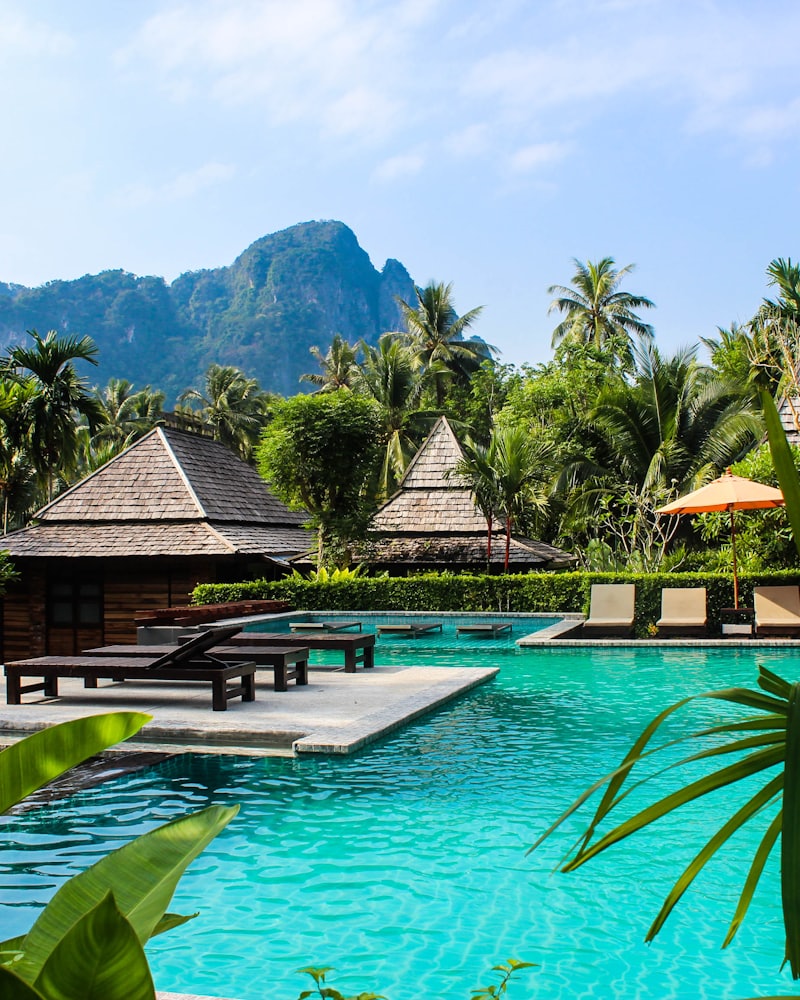 A pool among palms with limestone karsts rising behind, Krabi
