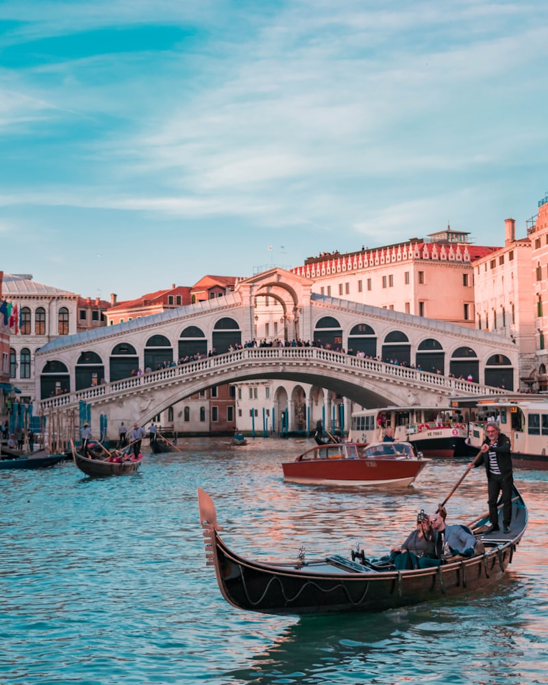 Gondolas on the Grand Canal beneath the Rialto Bridge at dusk